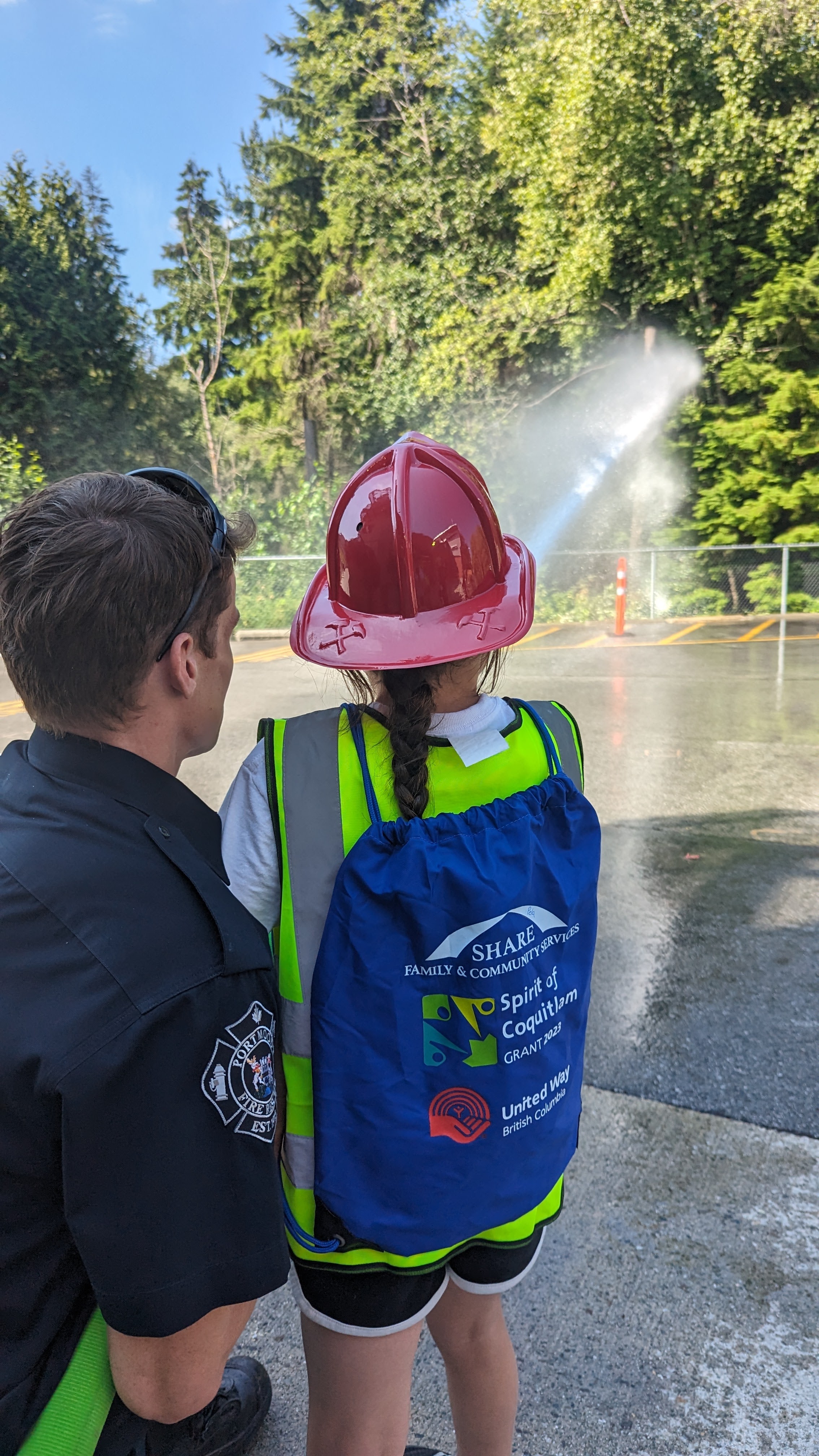 Port Moody Fire showing a summer camp participant how to use the fire hose.